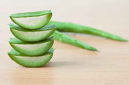 Aloe vera fresh leaves and slices with water drops on wooden background, closeupの写真素材