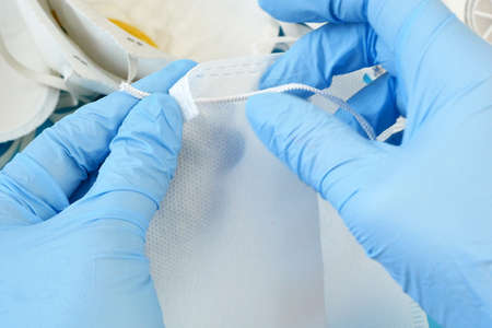 Hand in medical gloves makes medical mask, closeup