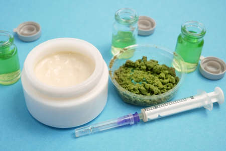 Cannabis cream cosmetic in dose with marijuana plant and oil on blue background. Cannabis cosmetics concept.の写真素材