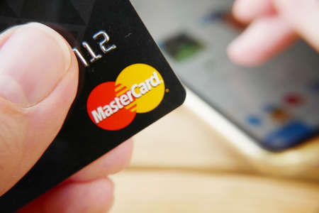 one hand takes bank card and other hand surfing in internet shop for buy foods. Using mobile phone, hold credit bank card, closeupのeditorial素材