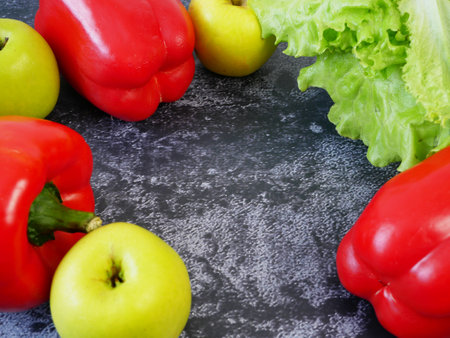 sweet red pepper, apple and lettuce on black background, frame, closeupの写真素材