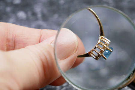 jeweler looking at ring with blue stone, jewerly inspect and verify, pawnshop concept, jewerly shop,...