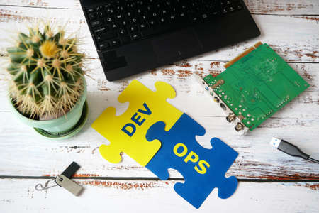 hands put on board words Dev and Ops. DevOps Concept for software engineering culture and practice...