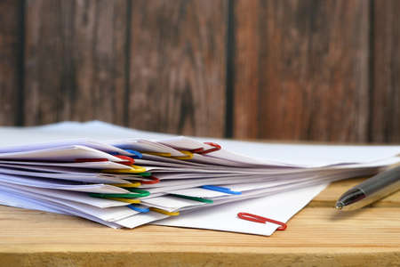 stack of many business documents with binder clips wooden table, closeup