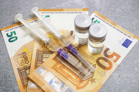 bottle of vaccine and money, money for purchase and production vaccine concept, closeupの写真素材