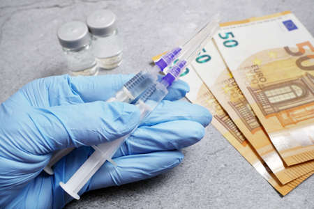 bottle of vaccine and money, money for purchase and production vaccine concept, closeup