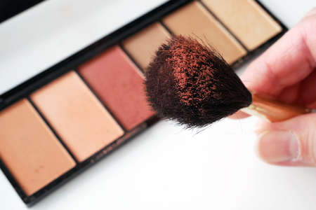 Eye shadows in brush in hand, Set Of Cosmetic Makeup Products. Nail polish, mascara, lipstick, eye shadows, brush, powder, lip gloss, closeupの写真素材