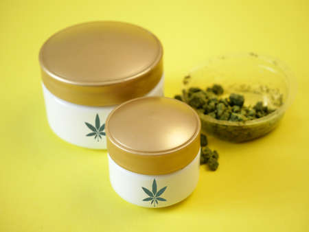 Cannabis cream cosmetic in dose with marijuana plant and oil on blue background. Cannabis cosmetics concept. Closeupの写真素材