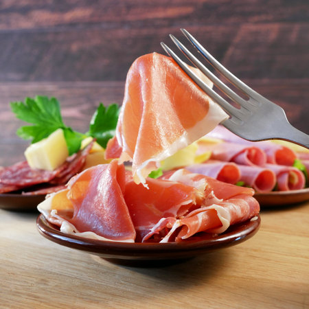 Cold Smoked Meat Plate, antipasto set platter wooden plate. Cold smoked meat plate with sliced ham, prosciutto, bacon. Copy space. Top view, closeupの写真素材