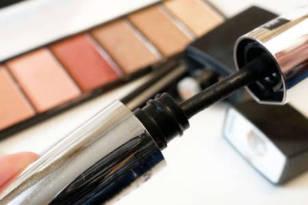 Mascara and set of cosmetic makeup products background. Lipstick, eye shadows, brush, powder, lip...