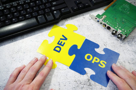 hands put on board words Dev and Ops. DevOps Concept for software engineering culture and practice of software development and operation, closeupの写真素材