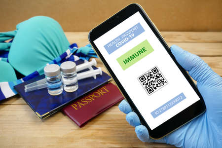 Vaccination passport on a mobile phone allowing travel in hand. Community or Health passport, closeupの写真素材