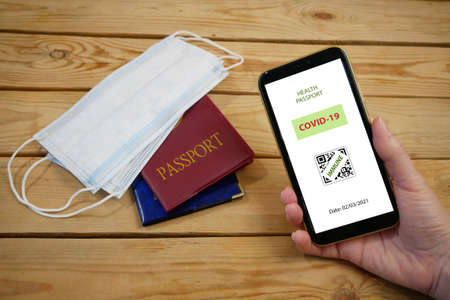 Vaccination passport on a mobile phone allowing travel in hand. Vaccination against the coronavirus Covid 19. Community or Health passport, closeupの写真素材