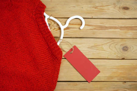 sweaters, bags on hangers on wooden background with red price tag, reasonable consumption concept, closeupの写真素材