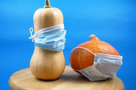 pumpkin wearing a face mask for protection from virus with halloween face jack-o-lantern. Halloween 2021 concept, closeupの写真素材