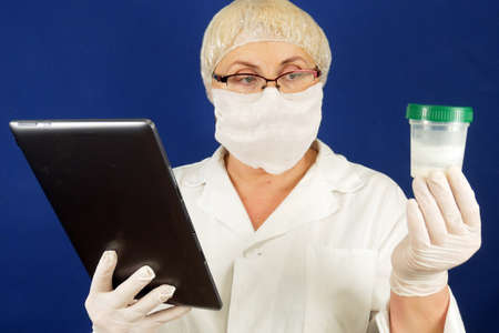 doctor holds test tube with sperm sam and tablet pc in sperm bank, indoors