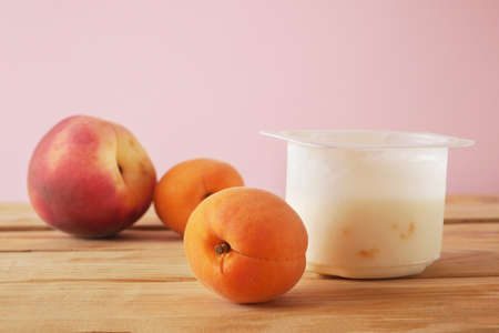 fresh tasty yogurt and fruits peaches and apricots on wooden background. Healthy Breakfast Concept. closeupの写真素材