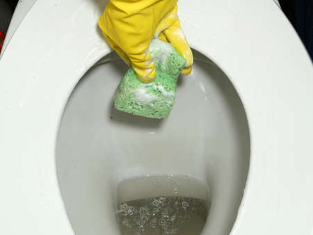 Hands in yellow rubber gloves cleaning toilet. Cleaning The Toilet with Toilet Brush. Closeupの写真素材
