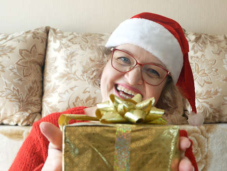 Woman with gifts for Christmas and New Year at home, smiling woman in santa helper hat with gift box, conceptの写真素材