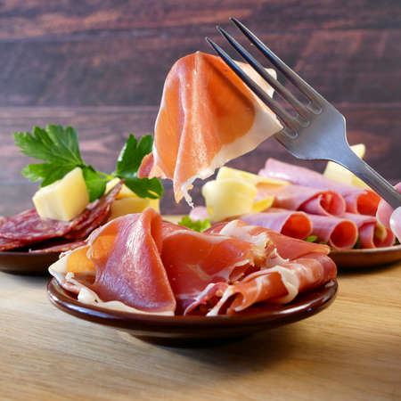 Cold Smoked Meat Plate, antipasto set platter wooden plate. Cold smoked meat plate with sliced ham, prosciutto, bacon. Copy space. Top view, closeupの写真素材
