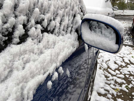 parked cars covered with snow in storm in city, first snow, closeup