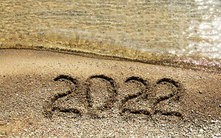 sign 2021 year numbers written on beach sand and sea waves background, merry xmas and happy new year, closeupの写真素材