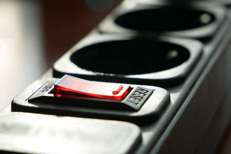 red lighting outlet switch on black Electric Extension Cord, closeup, macro