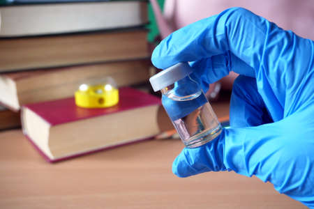 bottles and syringes of vaccine aganist covid-19 near book pile and school supplies, children...