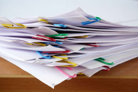 big stack of documents with binder clips on wooden table, closeupの写真素材