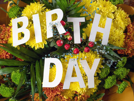 word birthday from white letters on big bunch with beautiful yellow chrysanthemums background, postcard, closeupの写真素材