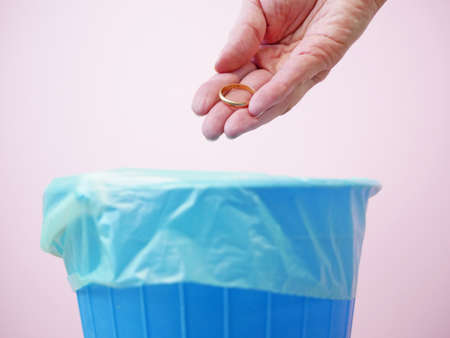 Hand throwing wedding ring away, trash bin, goodbye love and divorce concept, unhappy love, closeupの写真素材