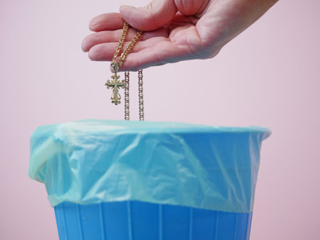 Hand throwing throw away the golden religious crossy, trash bin, goodbye god and religion concept, freedom concept, closeupの写真素材