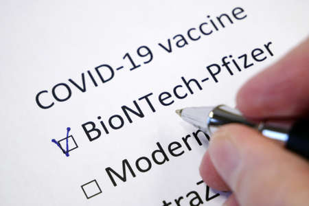 Hand daw in the questionnaire. Choice of vaccine: Comirnaty/Pfizer-BioNTech, AstraZeneca, Moderna, Johnson&Johnson. A closeup of female hand answering about a covid-19 question marking in a checkbox, closeupのeditorial素材