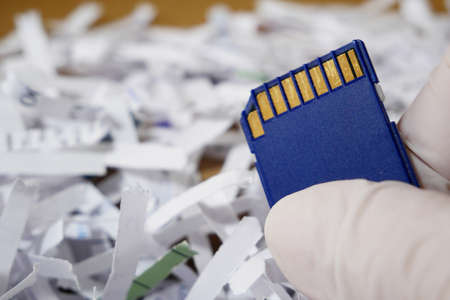 Top secret information on memory card among shredder paper, thief information concept, closeup