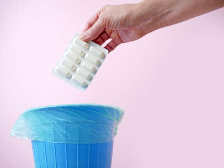 Hand throwing pills away, trash bin with pills and blisters inside, medecine in trashcan,...