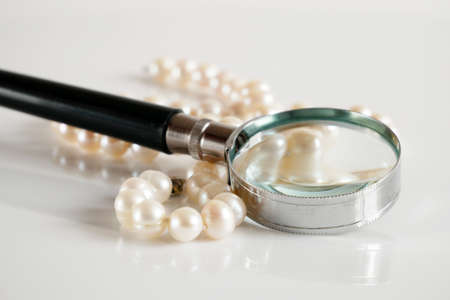 pearls necklace and magnifying glass on white backgrond, pawnshop concept, closeupの写真素材