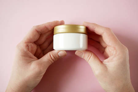 woman hands with cream cosmetic bottles on pink background, cold season hands skin protection. Hand skin care concept. natural organic beauty products. top view closeupの写真素材