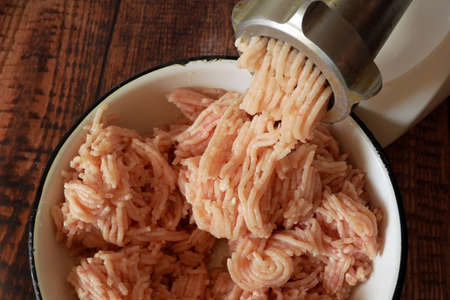 Production of minced chicken. Electric meat grinder makes minced meat. Process of cooking. close up