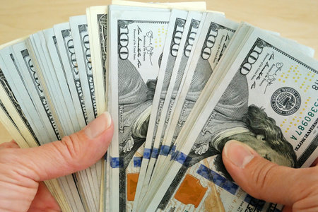 hand holding big stack of dollar USA money on wooden background. money cash closeup
