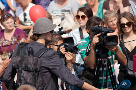 Correspondent and camera working in crowd. TV reporter working in parade, outdoorsのeditorial素材