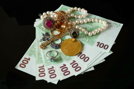 golden jewelery and stack of euro money on black background, pawnshop conceptの写真素材