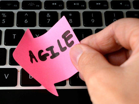 laptop keyboard and hand puts papaer arrow with agile title, software scrum agile board with paper...