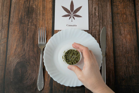 CBD Hemp extract and empty plate with knife and folk on the table. Cannabis drugs, marijuana buds and dry grass for eating. alternative food. top viewの写真素材