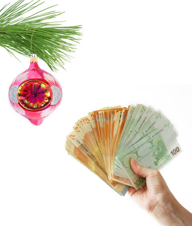Cristmas greeting card with new year balls and decorations and hand holding big stack of euro money, merry christmas and happy new year, wealth in new year conceptの写真素材