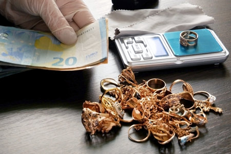 pawnshop worker counts money for gold jewelry on many golden and silver jewelry background....