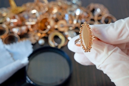 Pawnshop worker verify jewelry on many golden and silver jewelry and money background. Customers Buy and Sell Precious Metals, Jewels, Ancient Coins and Second Hand Appliances. Closeupの写真素材