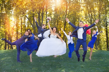 Newlyweds having fun with the guests in a meadow in the parkの写真素材