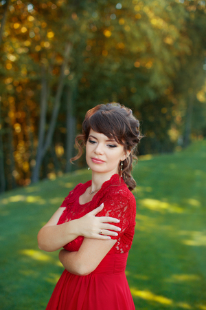 Girl in evening red dress in a warm summer dayの写真素材