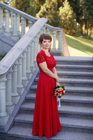Girl in evening red dress in a warm summer dayの写真素材