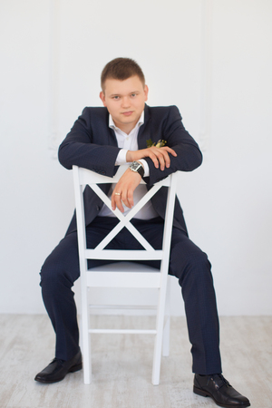 A man in a business suit sitting on a chair in the apartmentの写真素材